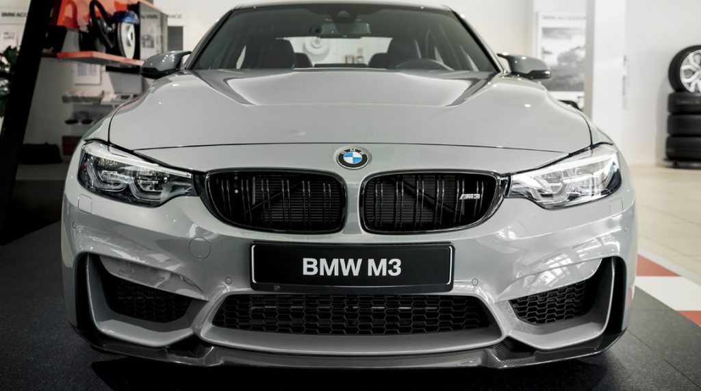 Front shot of a white BMW car inside an auto repair shop.