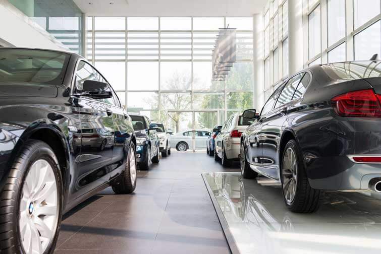 A wide shot of BMW cars for sale inside a BMW car dealership.